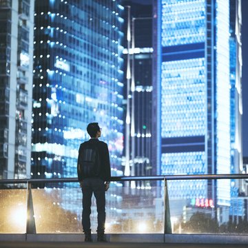A man looks at the skyline of a city at night